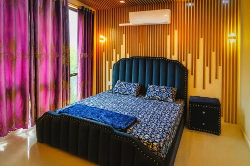 a bedroom with a bed with a blue head board at Modern Villa DHA in Lahore