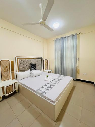 a large bed in a room with a ceiling fan at QD Apartment in Arusha