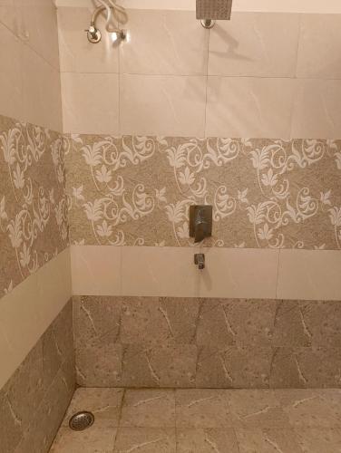 a bathroom with a shower with a tile wall at Rising Shemesh Home Stay in Udaipur