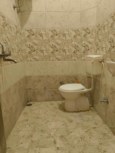 a bathroom with a toilet in a tiled room at Rising Shemesh Home Stay in Udaipur