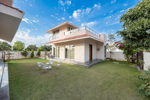 a house with a lawn and chairs in the yard at Urban Hideout - a mini farmhouse in Jaipur