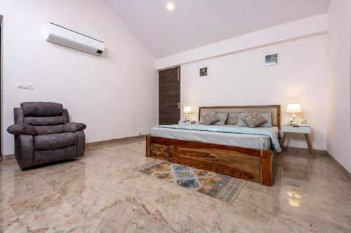 a bedroom with a bed and a chair at Urban Hideout - a mini farmhouse in Jaipur