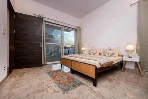 a bedroom with a bed and a large window at Urban Hideout - a mini farmhouse in Jaipur