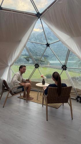 a man and woman sitting in chairs in a tent at Vollsnes Glamping in Hjelle