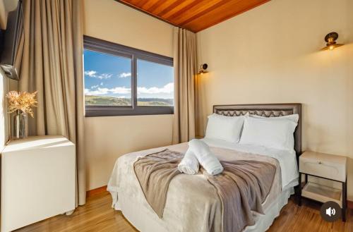 a bedroom with a bed with a large window at Casa do Vinho- condomínio Altos da Serra in Bom Jardim da Serra