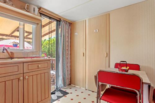 cocina con silla roja, mesa y ventana en Cocoon, en Sainte-Croix-du-Verdon