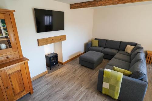 a living room with a couch and a tv at Honeysuckle Cottage in Hele