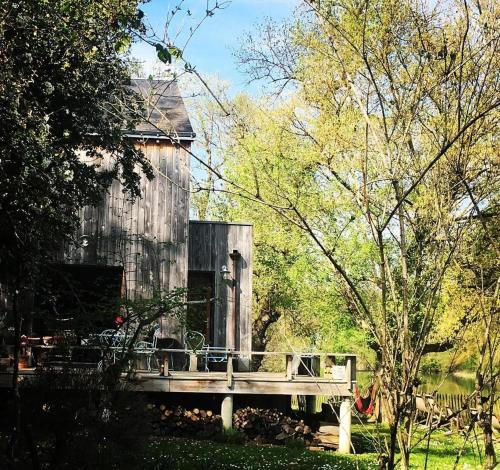an old barn with a wooden bridge in a yard at Une jolie Maison en bois au bord de l'Indre in Montbazon