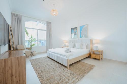 a white bedroom with a bed and a large window at 2 bedroom Tranquil Retreat in Ansam in Abu Dhabi