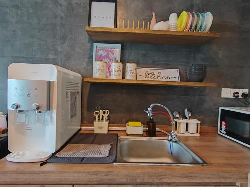 a kitchen counter with a sink and a microwave at Ipoh Sunway Onsen Suites and Tambun Guesthouse , 3-14pax 2parking by IWH in Ipoh