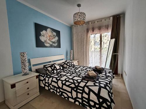 Schlafzimmer mit einem schwarzen und weißen Bett und einem Fenster in der Unterkunft Beautiful Apartment in Palm-mar