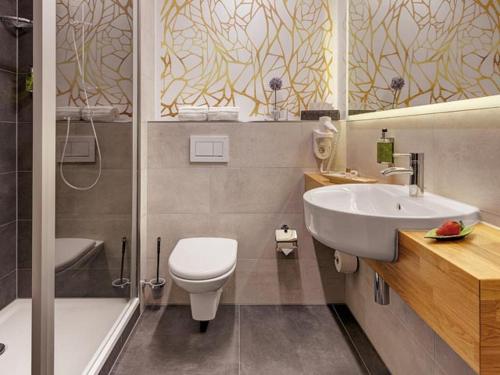 a bathroom with a sink and a toilet and a tub at Hotel Central in Hof