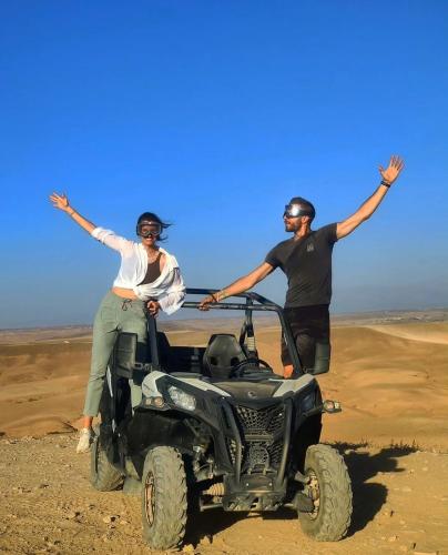 a man and a woman standing in a wheeler in the desert at Caravansérail Agafay by Dar Inacamp in El Mjed