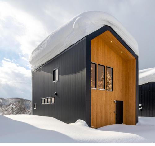 a building with a snow covered roof in the snow at Forest Avenue 64 in Niseko
