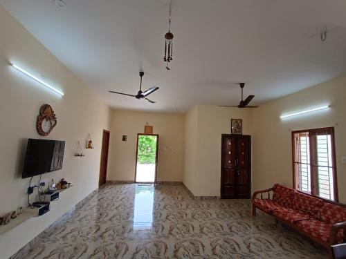 a living room with a couch and a tv at Sacred Arunachala View Homestay and Rooms in Tiruvannāmalai