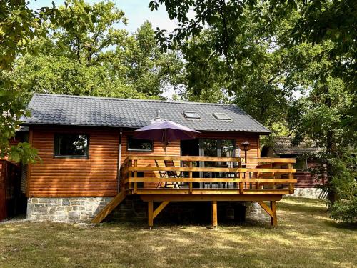 a wooden cabin with an umbrella on a deck at South Soul Cottage in Somme-Leuze