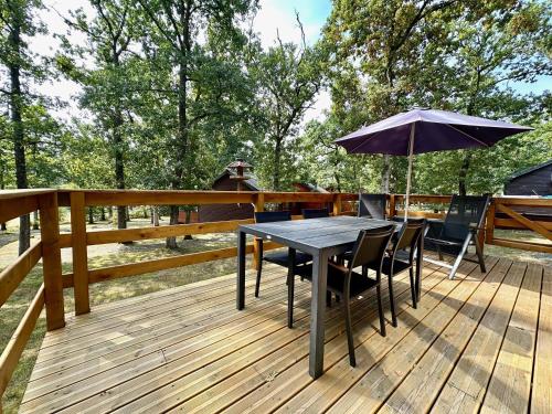 a table with chairs and an umbrella on a deck at South Soul Cottage in Somme-Leuze