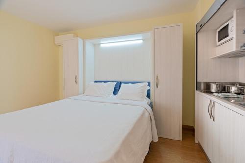 a bedroom with a white bed and a kitchen at Dom Pedro Garajau in Caniço