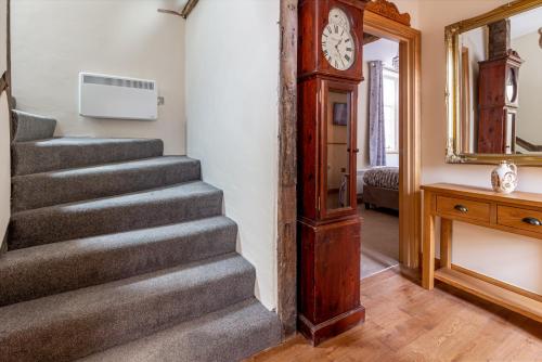 a staircase with a clock next to a mirror and a grandfather clock at The Merchants House in Hereford