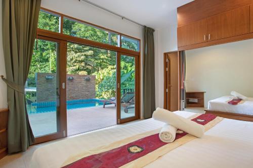 a bedroom with a bed and a large window at Heavenly Villas in Patong Beach