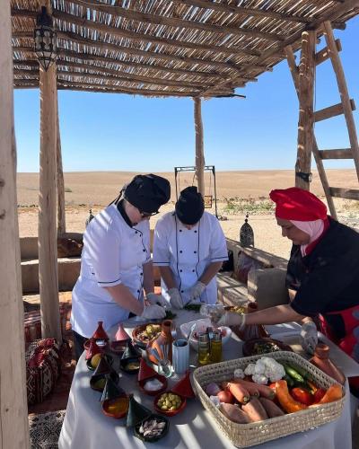 a group of people standing around a table with food at Dar Inacamp in El Mjed