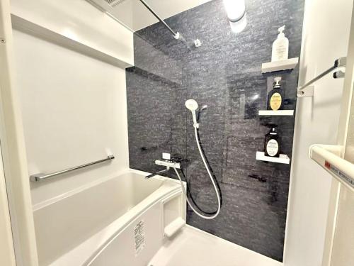 ein Badezimmer mit Dusche mit einer schwarz gefliesten Wand in der Unterkunft Shinjuku 歌舞伎町E3 in Tokio
