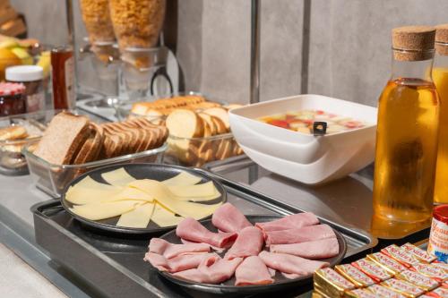 a buffet with meat and cheese and bread and a bottle of sauce at ibis budget Le Mans Centre in Le Mans
