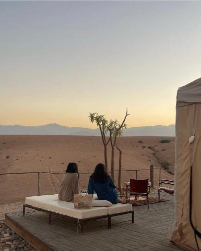 two women sitting on a bed in the desert at Dar Inacamp in El Mjed