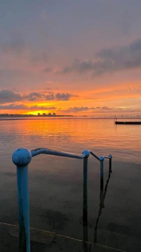 a pole in the water with a sunset in the background at De L'Etang in Saint Helier Jersey
