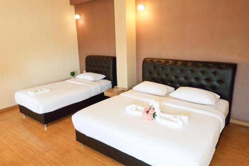 two beds in a hotel room with flowers on them at Triple Trees Hotel in Pathum Thani