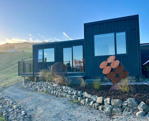 a green house with a tree stump in front of it at Harbour Hideaway in Dunedin