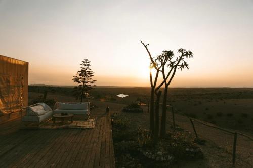 a couch on a deck with the sunset in the background at Dar Inacamp in El Mjed