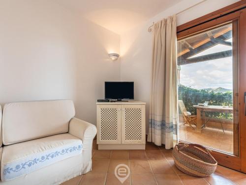 a living room with a couch and a tv and a window at Casa Perla in Domus de Maria