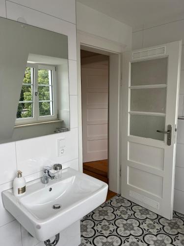 a white bathroom with a sink and a mirror at Elegantes Apartment in Villa in Ottobeuren