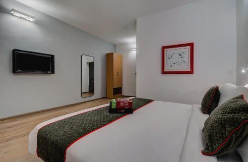 a bedroom with a bed with a tv on the wall at Super Townhouse T Nagar Chennai in Chennai