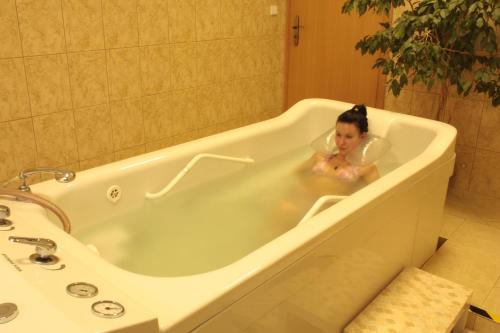 a woman is sitting in a bath tub at Hotel Bajkal in Františkovy Lázně