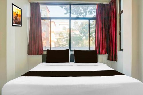 a bed in a room with a large window at Townhouse Central Viman Nagar in Viman Nagar