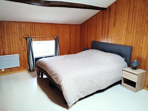 a bedroom with a bed with wooden walls and a window at Gîte de l'Église de la Pommeraie in La Pommeraie-sur-Sèvre