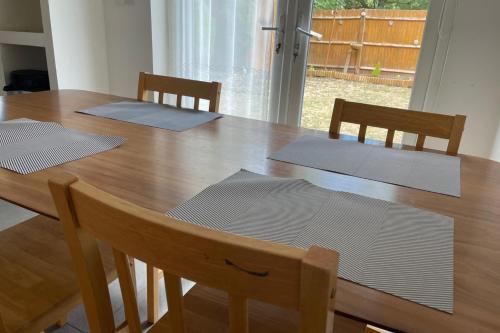 a dining room table with four chairs and a wooden table at 4-Bed Barnwell Retreat- Sleeps 9 Garden & Parking in Stevenage