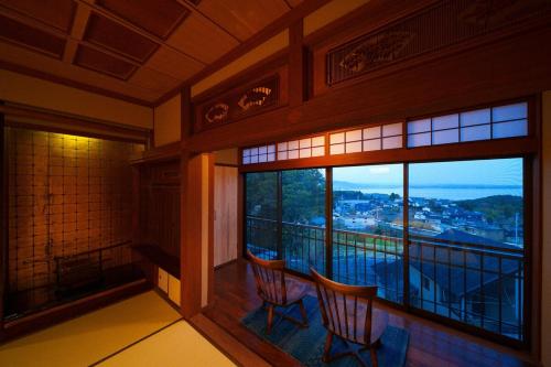 a room with two chairs and a balcony with a view at Beppu Kura in Beppu