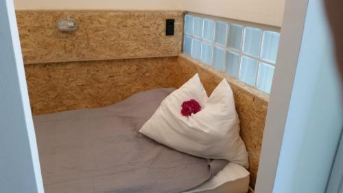 Una cama con una almohada blanca con una flor roja. en Stylish Living, en Bad Gastein