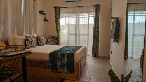 a bedroom with a bed and a tv in it at La Maison de Canelya in Cotonou