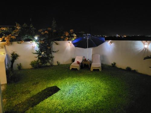 a table and chairs and an umbrella in a yard at night at Diar Mira in Kelibia