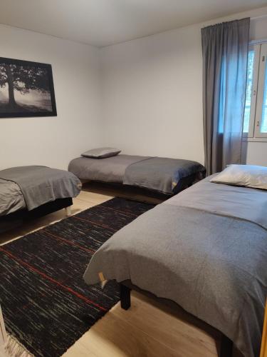 a bedroom with two beds and a rug at Kodikas talo lammen rannalla in Raahe