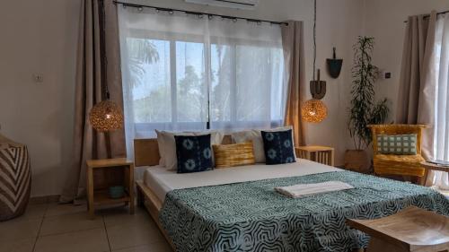 a bedroom with a bed with a window at La Maison de Canelya in Cotonou