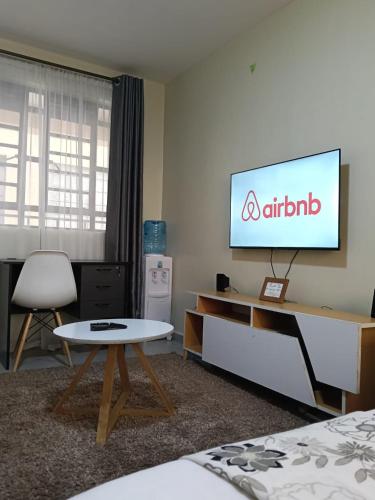 a room with a tv and a table and a chair at Comfy Studio in Ngong