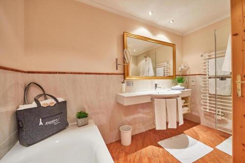 a bathroom with a tub and a sink and a mirror at Superior Sport und Familienresort Alpenblick in Zell am See