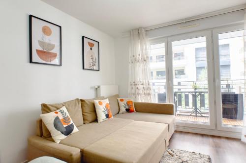 un soggiorno con un divano e una grande finestra di Appartement Elégant a Saint-Ouen