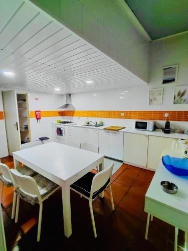 a large kitchen with a white table and chairs at Brincalquimia in Setúbal
