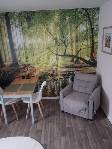 a room with a table and a couch and a forest mural at Nähe Plohn Park - FEWO mit Spielzimmer und Balkon, DZ in Auerbach
